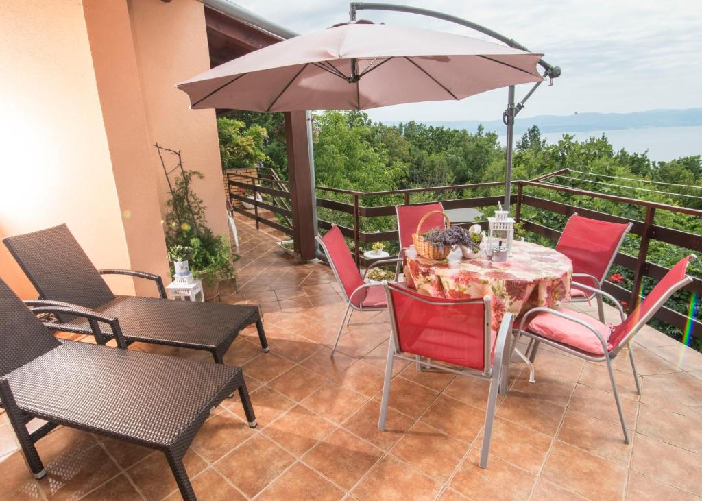 un patio con mesa, sillas y sombrilla en Apartment Alba, en Medveja