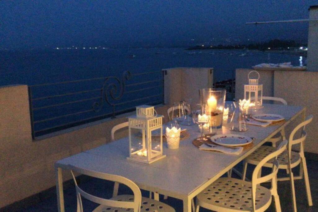 una mesa en un balcón con vistas al océano en Mansarda Marinello, en Oliveri