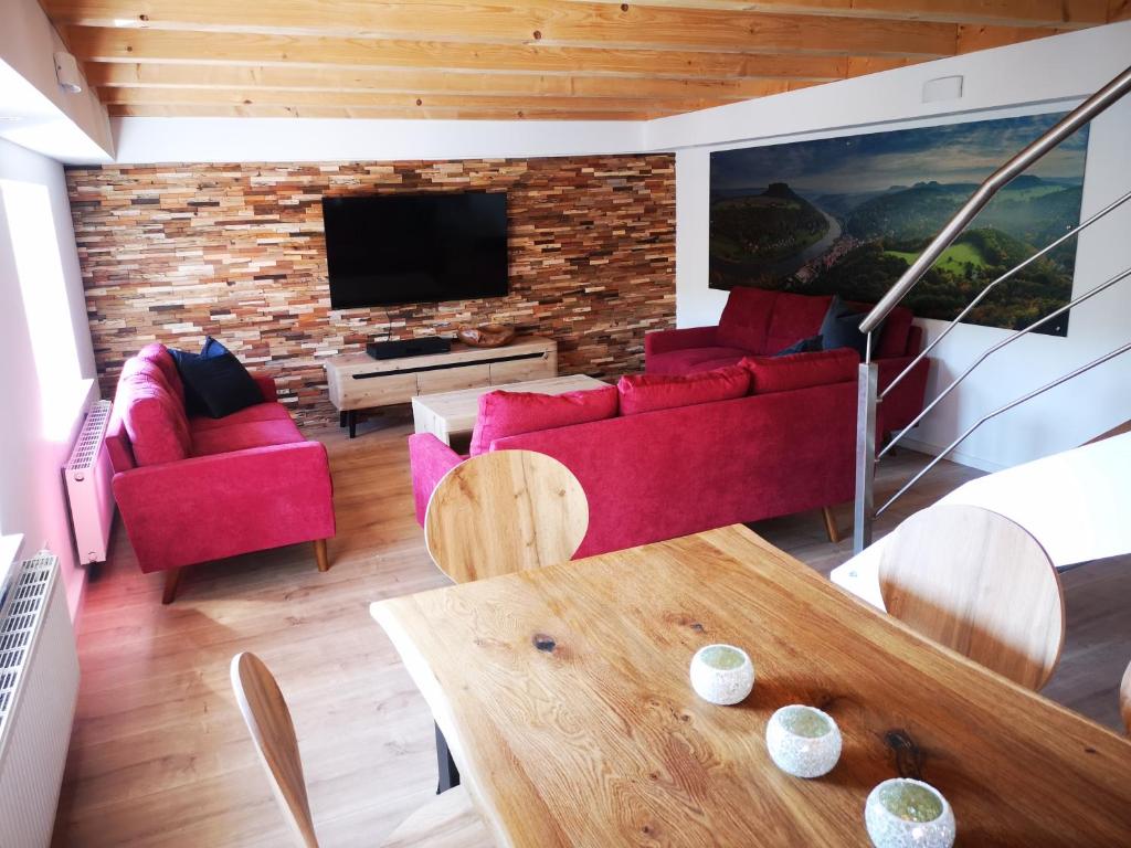 ein Wohnzimmer mit roten Möbeln und einem Flachbild-TV in der Unterkunft Ferienhaus Elbsicht in Pirna