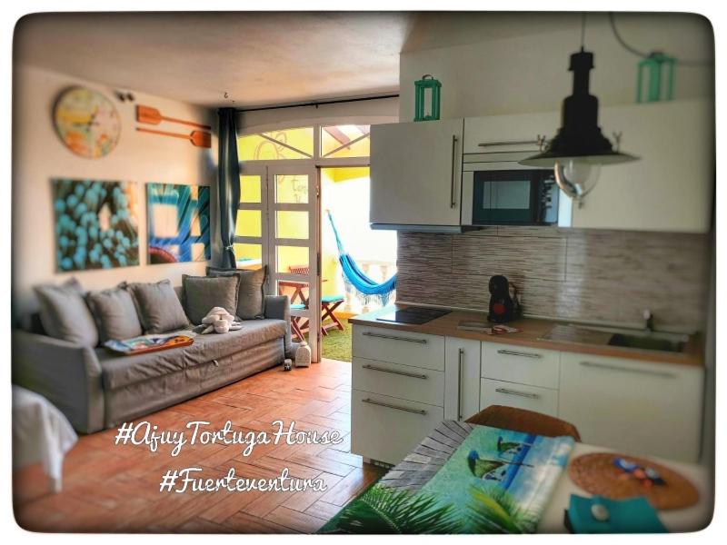 a kitchen and a living room with a couch at Ajuy Tortuga House in Ajuy
