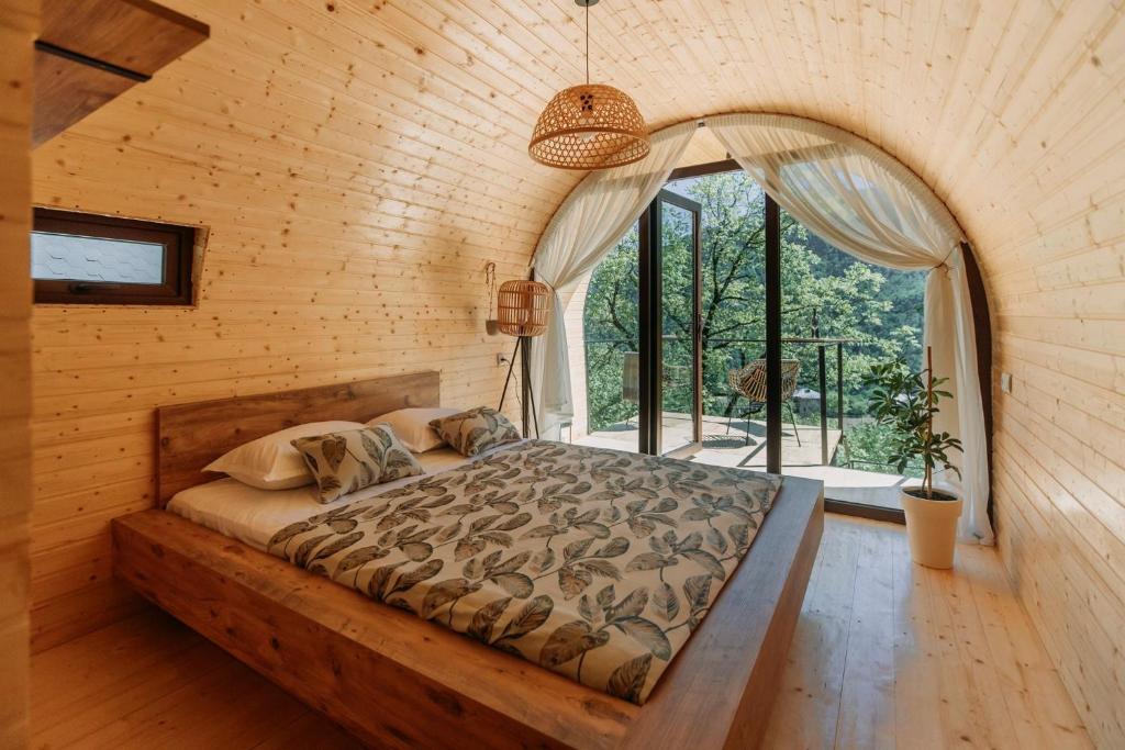 Bett in einem Zimmer mit einem großen Fenster in der Unterkunft Woodhide - Cottages near Batumi, Georgia in Zeda Ch'khutunet'i