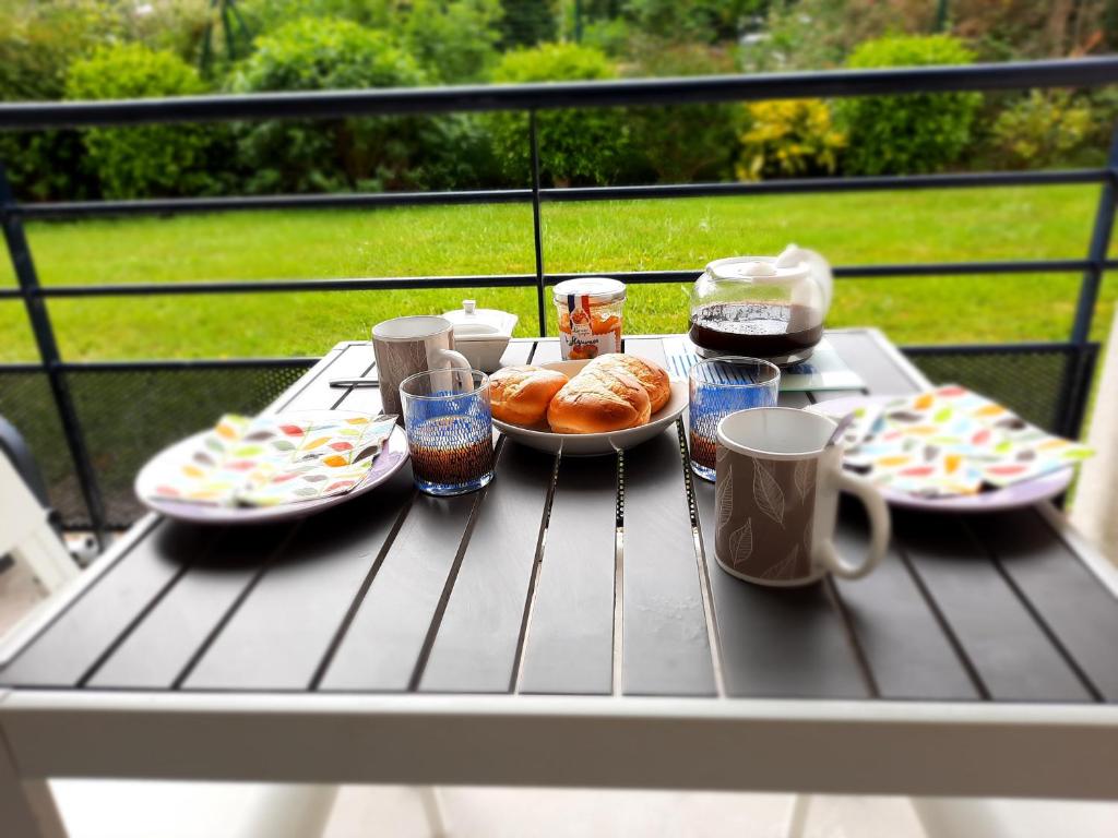 a table with plates of food and drinks on a balcony at L'Océanide - Appartement avec balcon-terrasse et parking privé in Pont-lʼAbbé