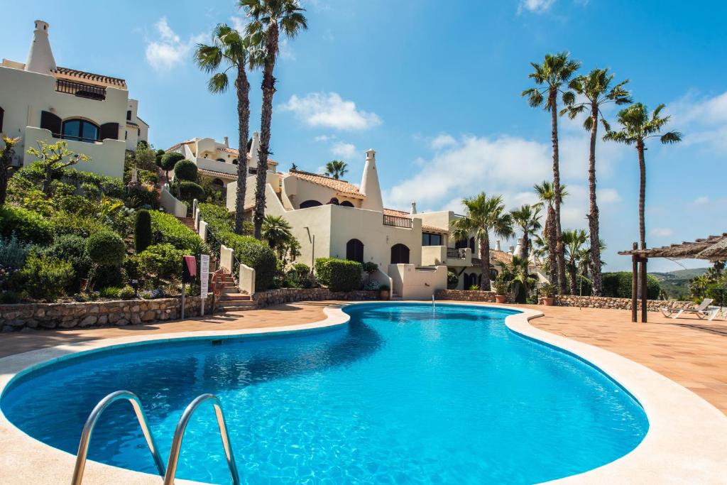 uma piscina em frente a uma casa com palmeiras em Luxuriöse und großräumige Villa mit Community Pool, Sicht auf das Mittelmeer sowie dem Mar Menor, La Manga Club em Atamaría