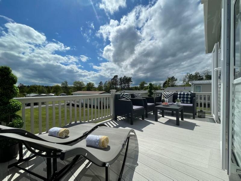 a patio with chairs and tables on a deck at Hot Tub 9 The Fairways in Alnwick