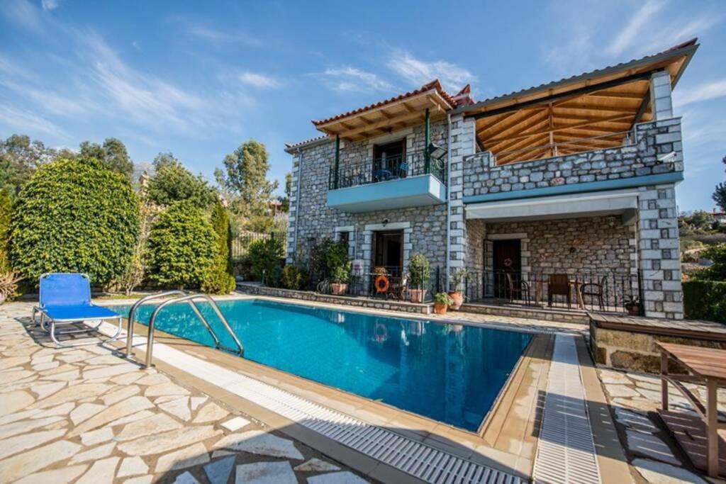 una villa con piscina di fronte a una casa di Kelly's Villa in Stoupa a Neokhórion