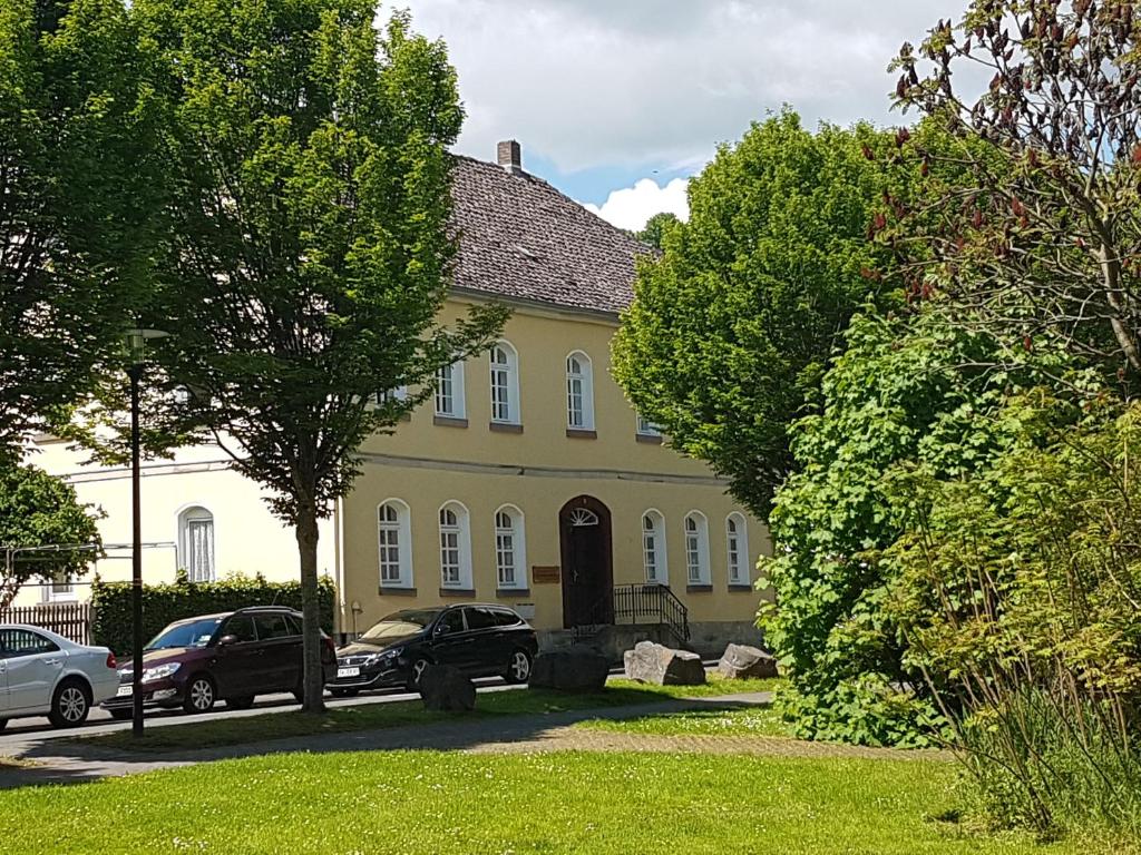 een geel huis met auto's ervoor geparkeerd bij Haus Salinenblick in Bad Sooden-Allendorf