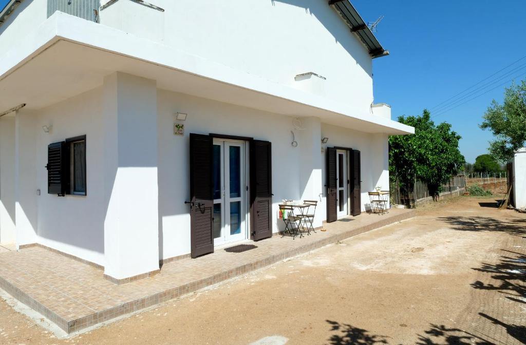 una casa bianca con persiane nere e un patio di Alloggi in Villa Potenza a pochi minuti da Gallipoli a Galatone