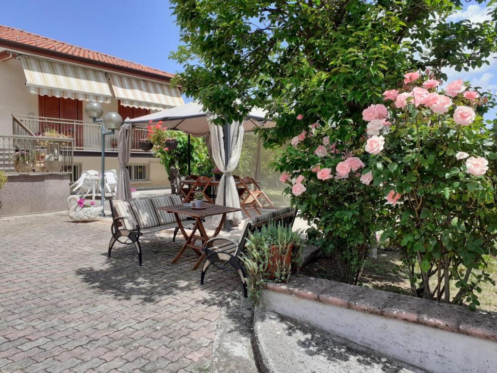 un patio con mesa, sombrilla y rosas en Lo Campo, en Montella