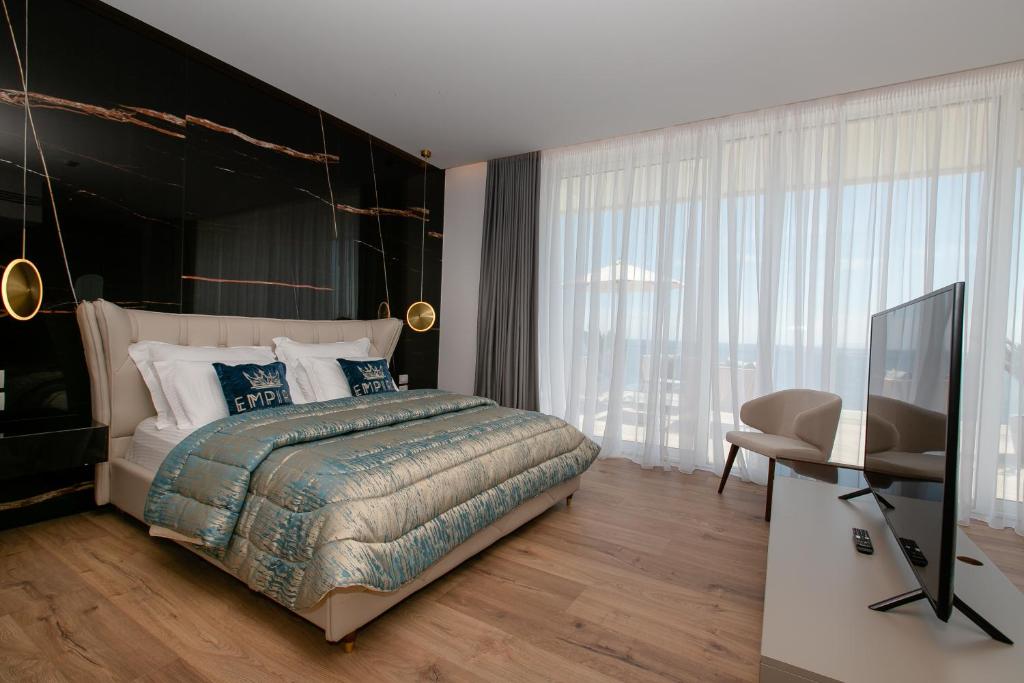 a bedroom with a bed and a desk and a television at Empire Beach Resort ADULTS ONLY in Dhërmi