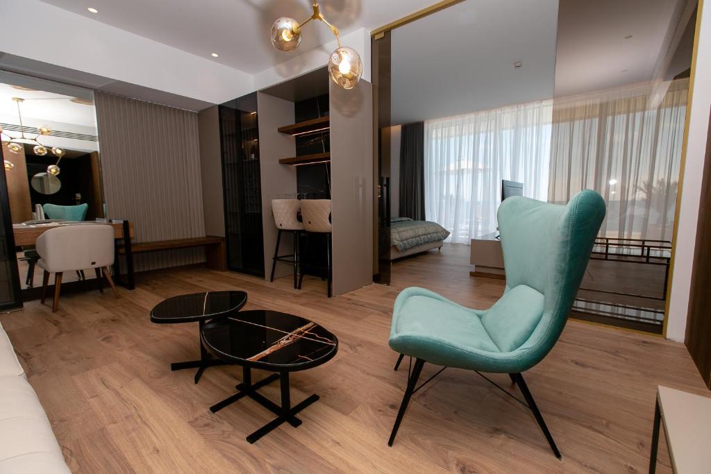 a living room with a blue chair and a table at Empire Beach Resort ADULTS ONLY in Dhërmi
