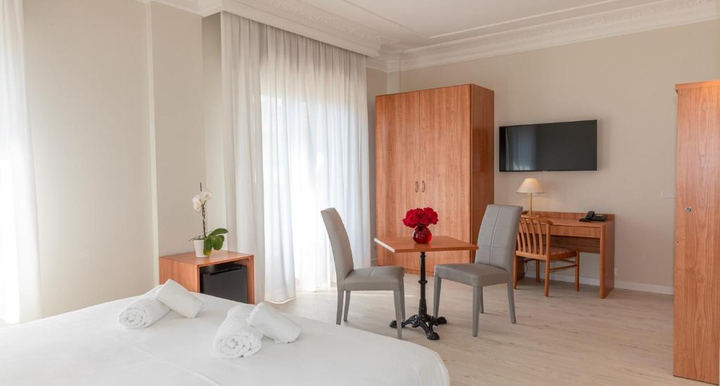 una camera d'albergo con letto, tavolo e scrivania di Hotel Smeraldo a Lido di Jesolo