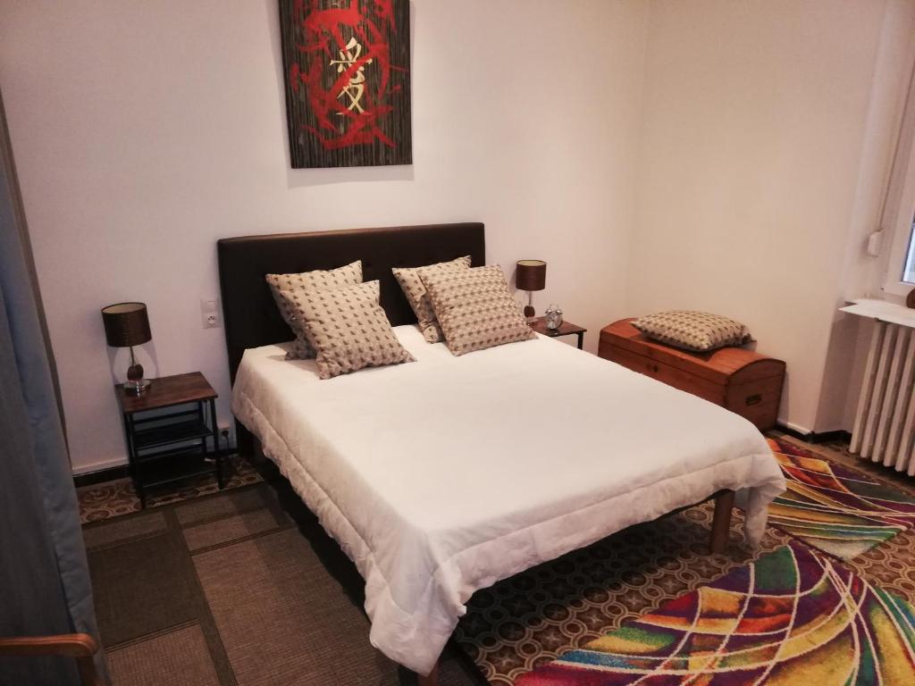 1 dormitorio con 1 cama grande con sábanas y almohadas blancas en LA MAISON DU BIEN ETRE o en Alès