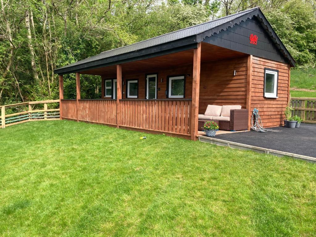 a wooden cabin with a couch in a yard at Kabin in the woods in Llandybie