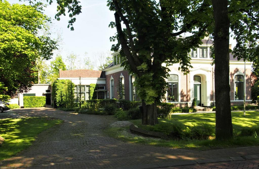 a large white house with trees in front of it at De oude dokterspraktijk in Zuidhorn