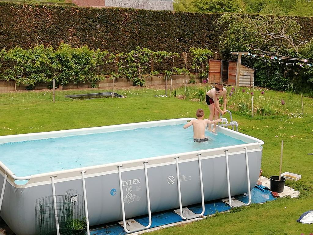 two men standing in a pool in a yard at Villa Maëlla en Normandie- chambres tout confort - SPA in Saint-Michel-Tubœuf