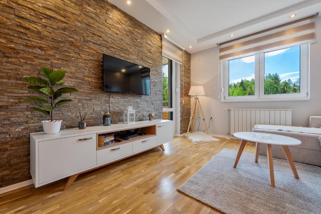 a living room with a tv on a brick wall at Carpe Diem in Zlatibor