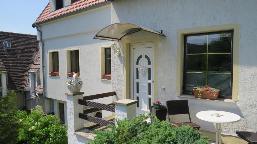 uma casa com um alpendre com uma mesa e uma porta em Ferienhaus Elbsommer am Weinberg II em Meissen