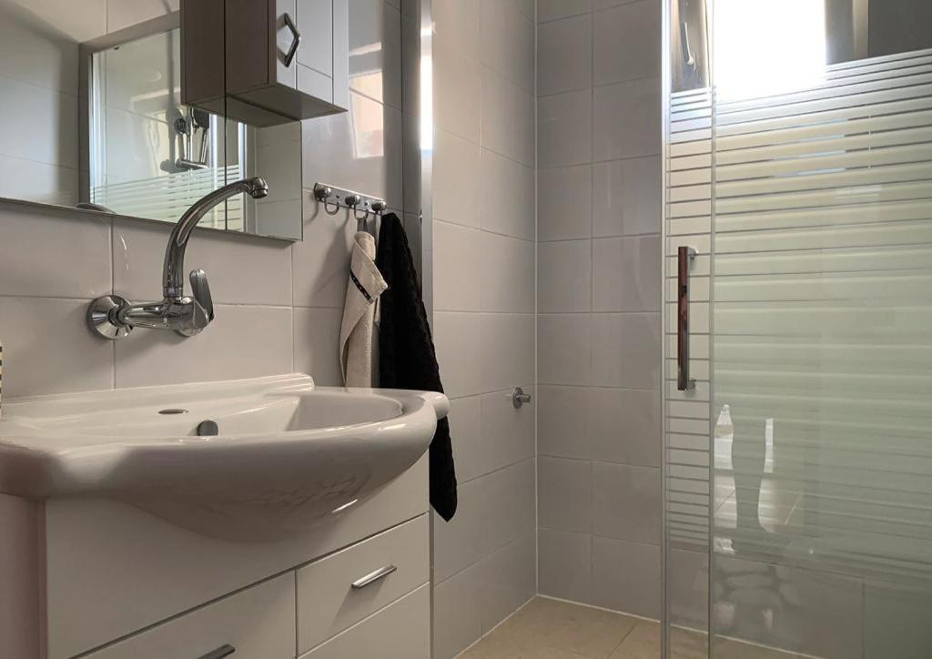 a white bathroom with a sink and a shower at Apartments Neda in Primošten