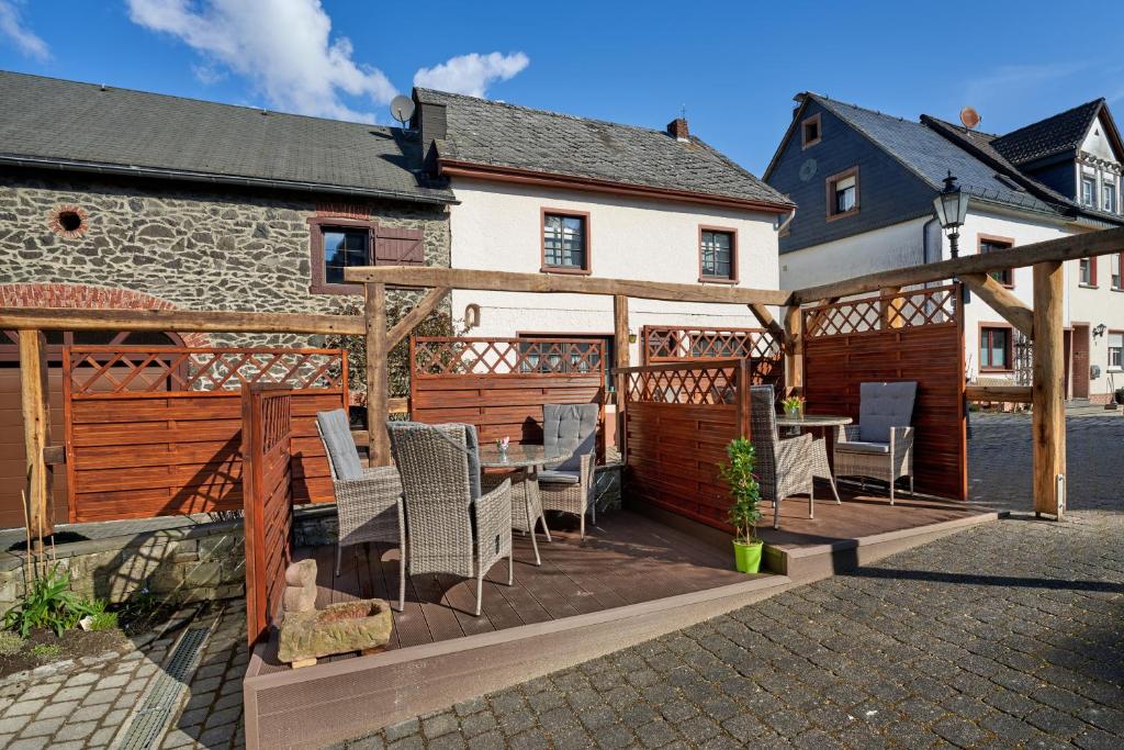 eine Terrasse mit einem Tisch und Stühlen vor einem Haus in der Unterkunft Ferienwohnungen Eifelstuben mit Charme - am See, nahe Burg in Ulmen