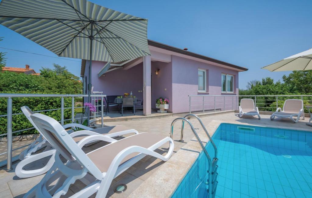 uma piscina com cadeiras e um guarda-sol ao lado de uma casa em Adorable Holiday House Lilla-with pool-near Old Town Labin em Labin
