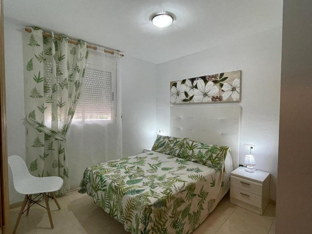 um quarto com uma cama, uma cadeira e uma janela em ACAPULCO III MARINA DÓR em Oropesa del Mar