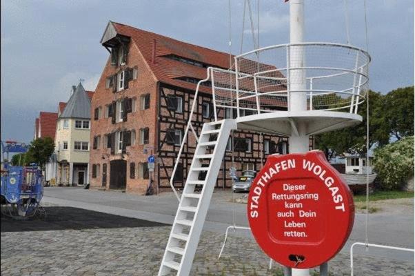 a red sign in front of a house with a ladder at Der Speicher in Wolgast