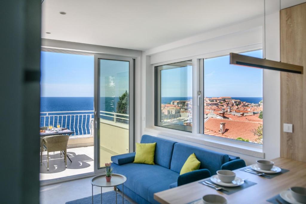 a living room with a blue couch and large windows at Villa Leoni in Dubrovnik