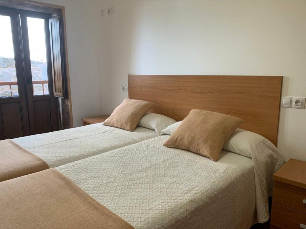 two beds in a bedroom with a large window at Apartamentos San Guillermo in Finisterre