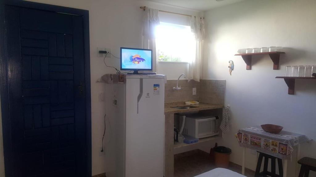 cocina con nevera y TV en la parte superior en Apartamento perto de praia Dos Anjos 2 en Arraial do Cabo