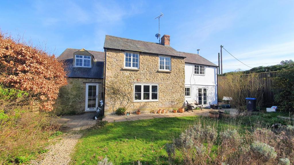 una gran casa de ladrillo con un patio delante en Glenfield Cottage - Secluded Luxury deep in the Oxfordshire Countryside, en Wilcote