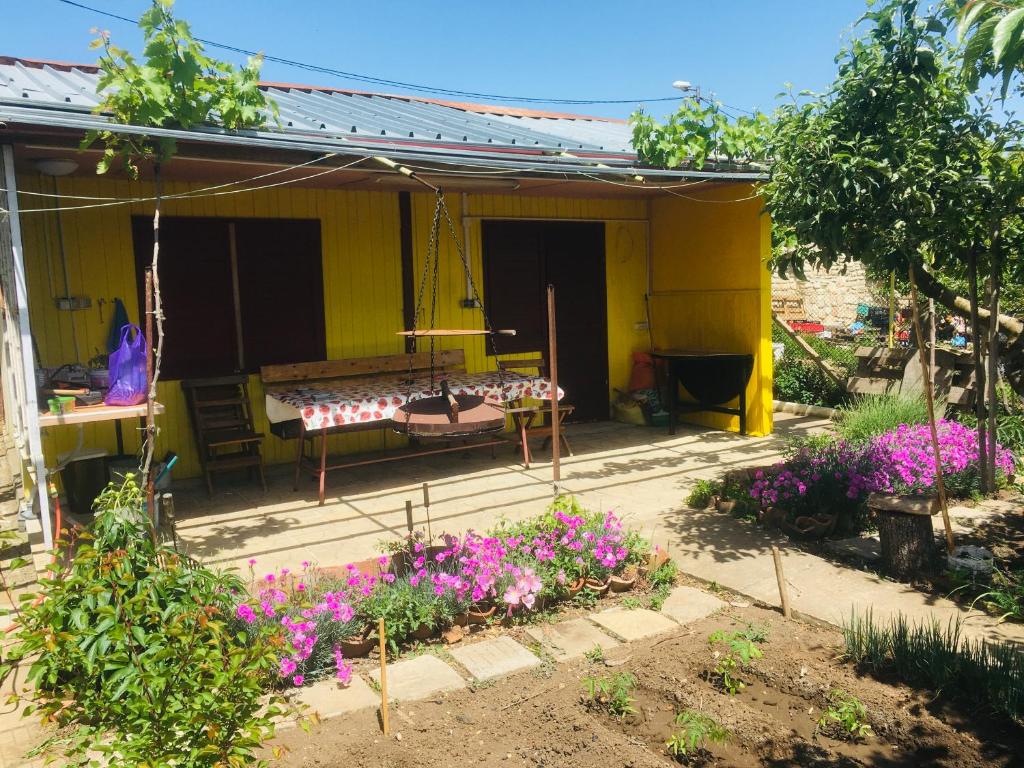 una casa amarilla con flores púrpuras en el patio en Бунгало- Bungalow, en Kavarna