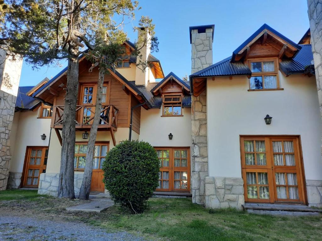 a large house with wooden doors and trees at Apart Hotel Bungalows El Viejo Cipres in San Carlos de Bariloche