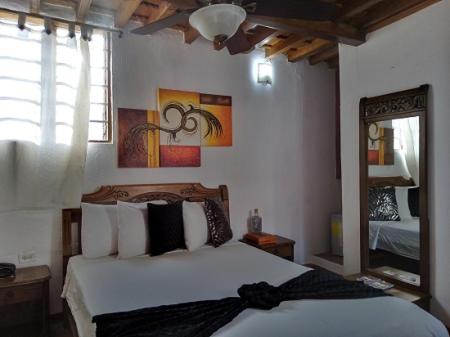 1 dormitorio con 1 cama con sábanas blancas y espejo en Casa Abril II, en Cartagena de Indias