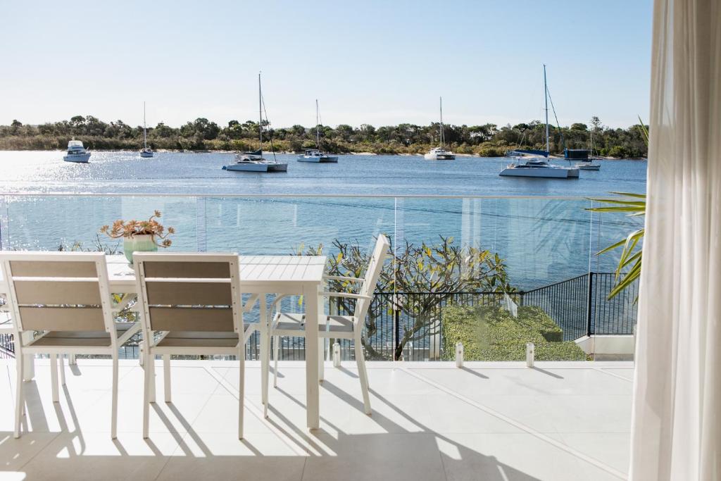 una mesa y sillas en un balcón con vistas al agua en Aqua Linea, en Noosa Heads