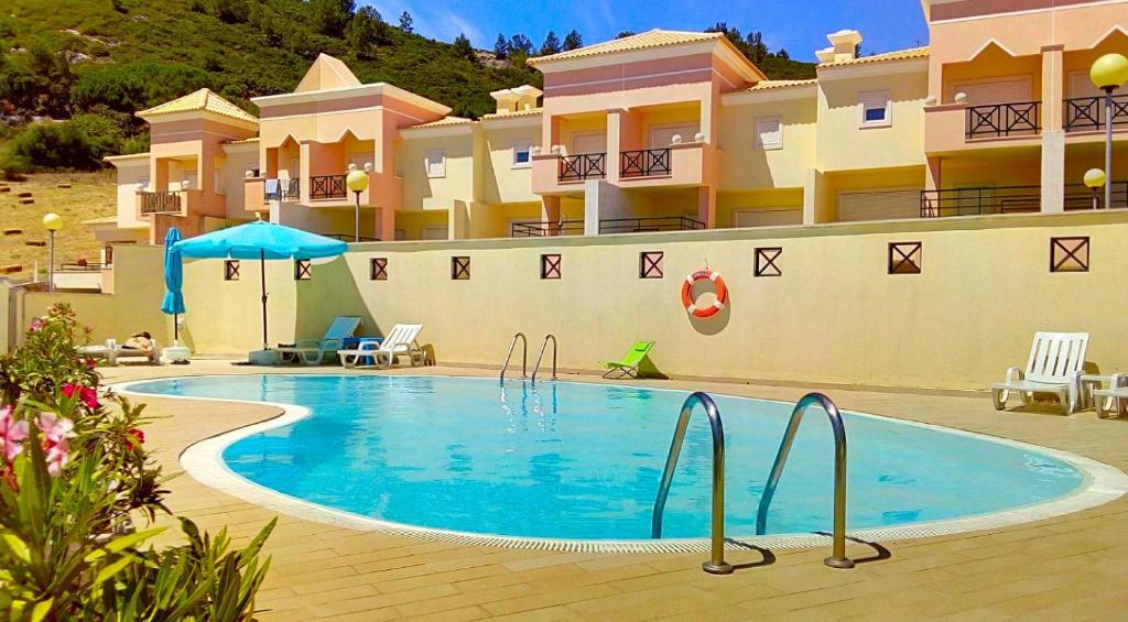 a swimming pool in front of a building at Oceanview Duplex shared Pool & Beach Sesimbra in Sesimbra