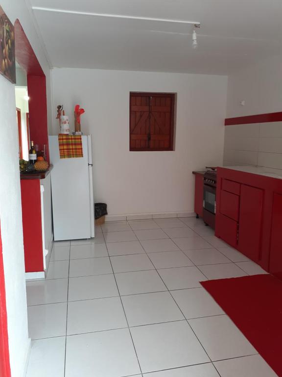 uma cozinha com armários vermelhos e piso em azulejo branco em Divima em Sainte-Anne