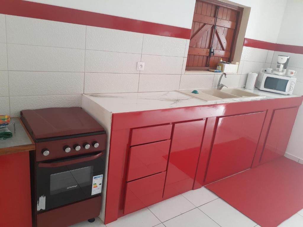 a red kitchen with a stove and a microwave at Divima in Sainte-Anne