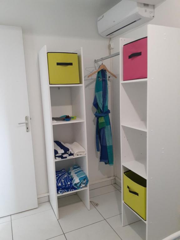a closet with white shelves and colorful boxes at Divima in Sainte-Anne