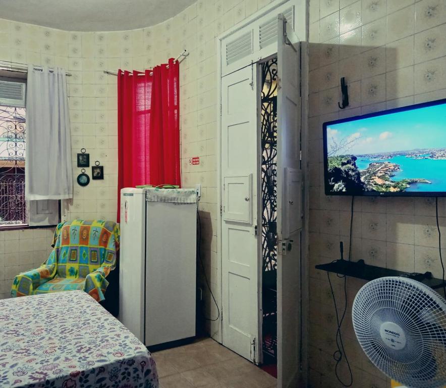 um quarto com um frigorífico e uma televisão de ecrã plano em Kitnet Mobiliada em São Luís