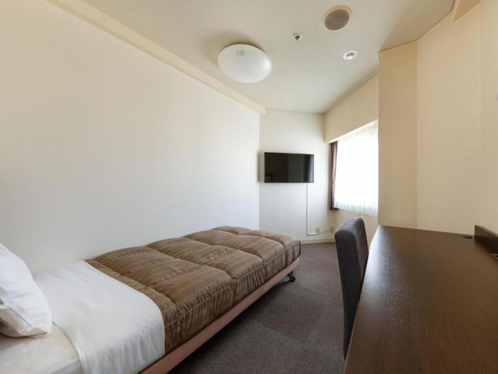 a bedroom with a bed and a table and a television at The OneFive Okayama - Vacation STAY 41839v in Okayama