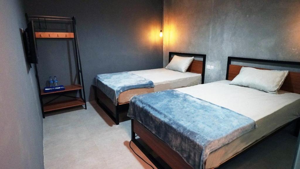 Habitación de hotel con 2 camas y mesita de noche en Hostel 18 Pasangan Butuh Surat Nikah en Bandung