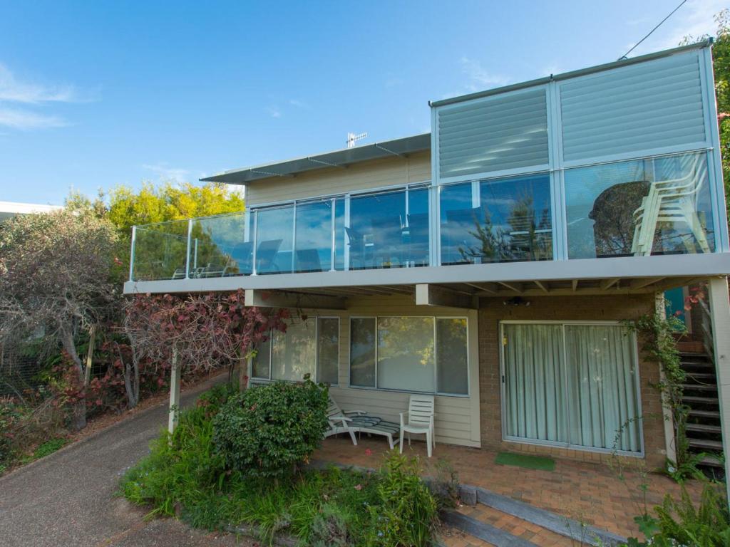 a house with glass windows and a balcony at Seascape in Pambula Beach