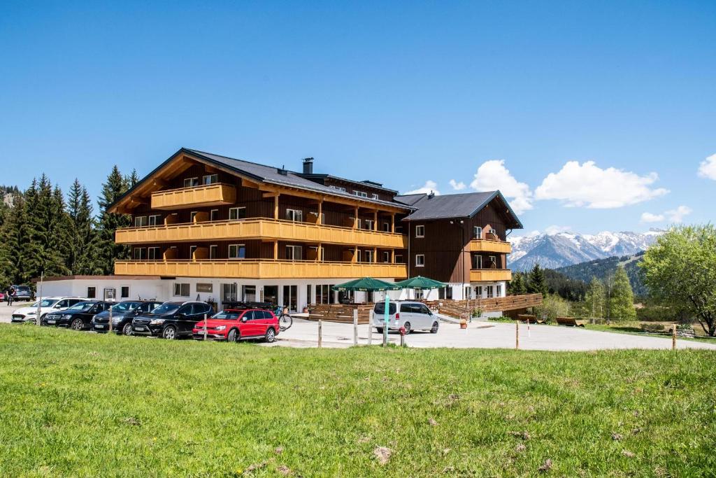 ein großes Gebäude mit Autos auf einem Parkplatz in der Unterkunft Alpengasthof Hörnlepass in Riezlern
