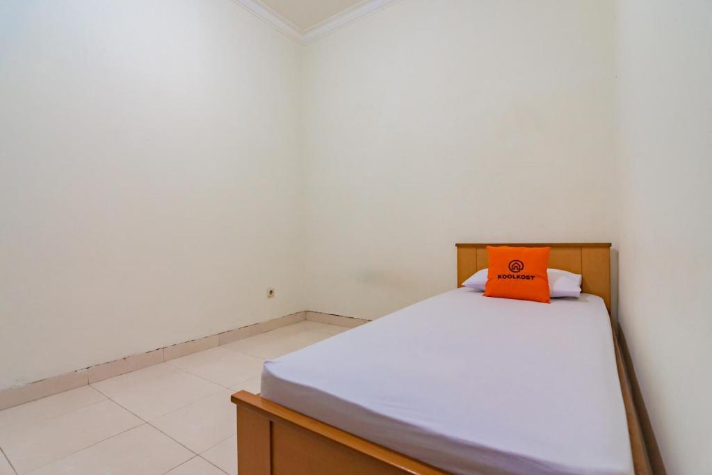 a bedroom with a bed with an orange pillow on it at Koolkost near Riau Junction Mall (Minimum Stay 6 Nights) in Bandung