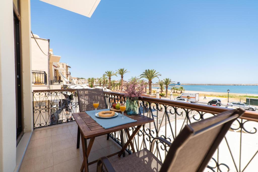 a table on a balcony with a view of the beach at Blue Sea Relax Apartment in Rethymno
