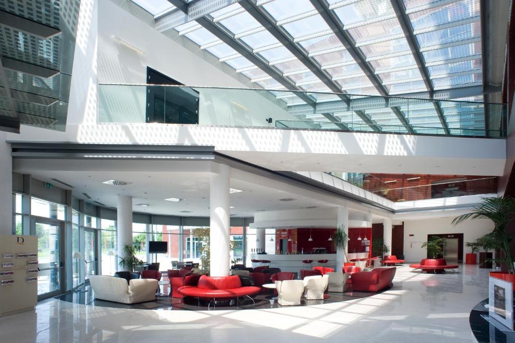 a large lobby with red and white furniture and a glass ceiling at Domina Milano Fiera in Novate Milanese