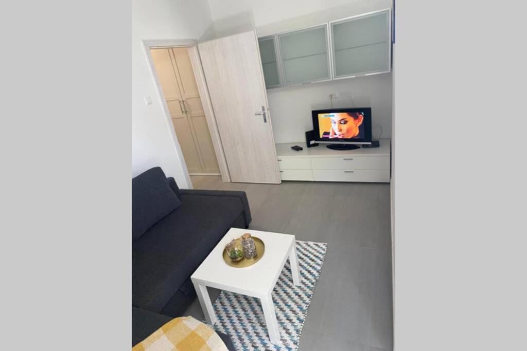 un soggiorno con divano, tavolo e TV di Lexi apartma a Capodistria