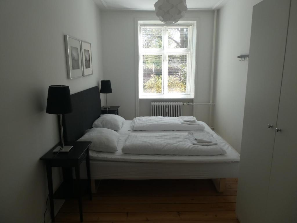 a white bedroom with a bed with a window at Lillegrund in Copenhagen