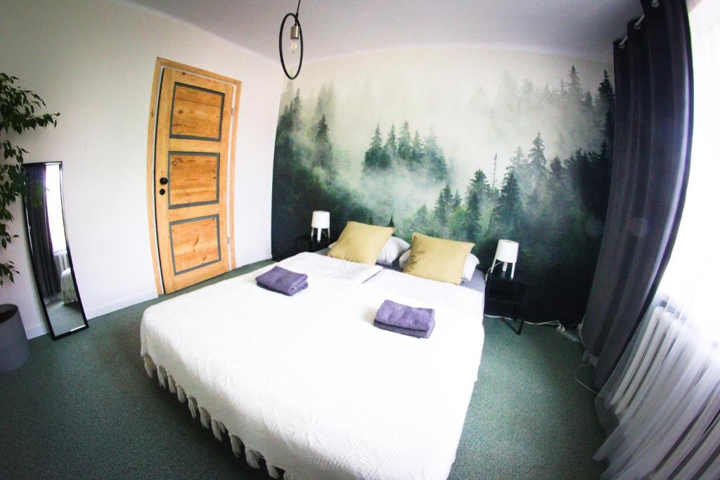 Uherce MineralneにあるBezpieczna Przystań - Apartamentyのベッドルーム1室(壁に絵画が描かれた白い大型ベッド1台付)
