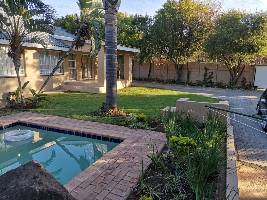 a house with a palm tree and a swimming pool at Rooikrans Guest House in Johannesburg